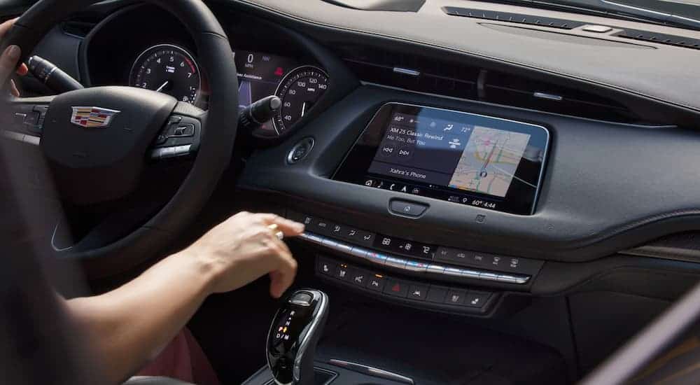 A hand touching the infotainment screen in a 2020 Cadillac XT4 is shown from inside the vehicle.