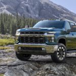 A blue 2020 Chevy Silverado 2500 HD is parked on rocks with a mountain in the background.