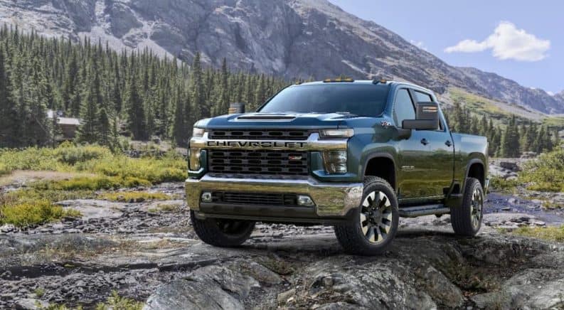 A blue 2020 Chevy Silverado 2500 HD is parked on rocks with a mountain in the background.