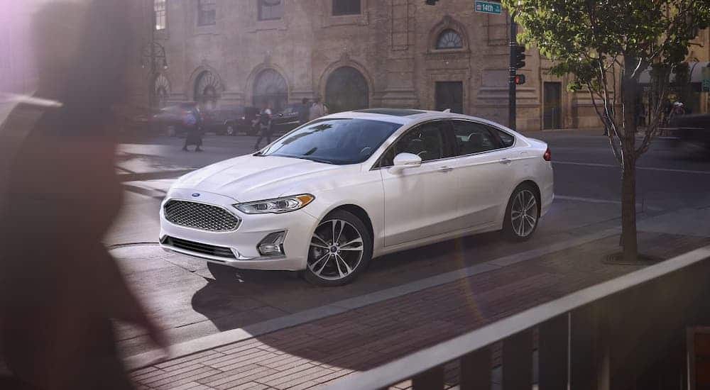 A white 2020 Ford Fusion is parked on a city street.