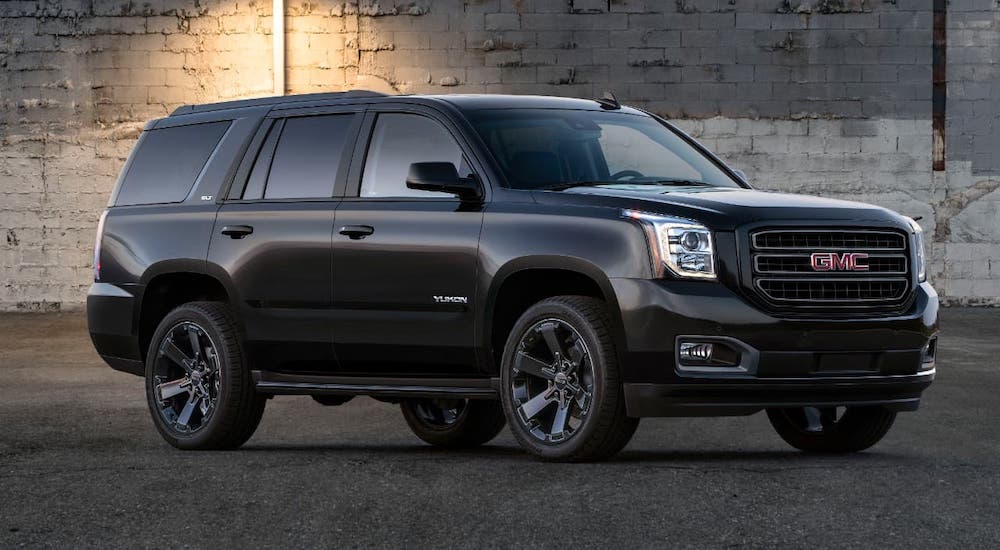 A black 2020 GMC Yukon Graphite Edition is parked in front of a white brick wall.