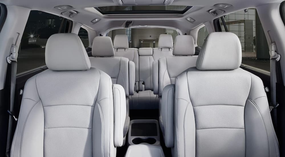 The white interior of a 2021 Honda Pilot is shown from the front seats backward.