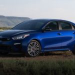 A blue 2020 Kia Forte is parked off-road in front of distant hills after winning the 2020 Kia Forte vs 2020 Hyundai Elantra comparison.
