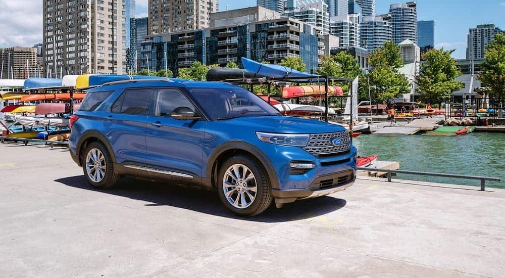 A blue 2020 Ford Explorer is parked on a pier in front of canoes.