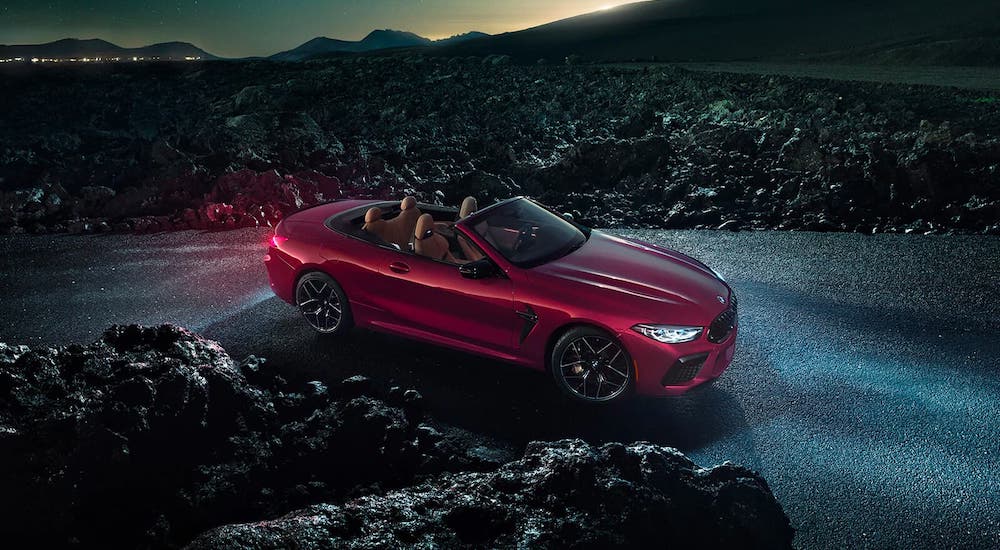 A red 2020 BMW M8 Convertible is parked in a desert at night.