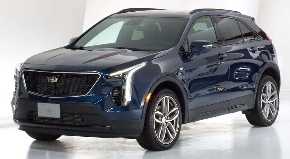 A small Cadillac SUV model, a blue 2020 Cadillac XT4, is parked in a white showroom.