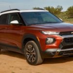 A new Chevy SUV, a red 2021 Chevy Trailblazer, is driving on a dirt road.
