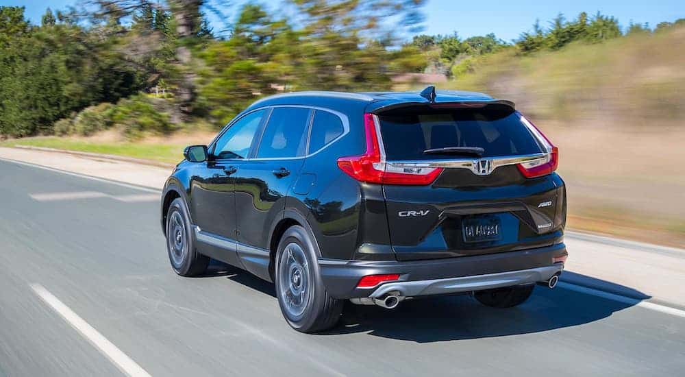 A gray 2019 Honda CR-V is driving away on a rural highway.