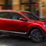 A red 2020 Honda CR-V is driving around a corner on a city street.