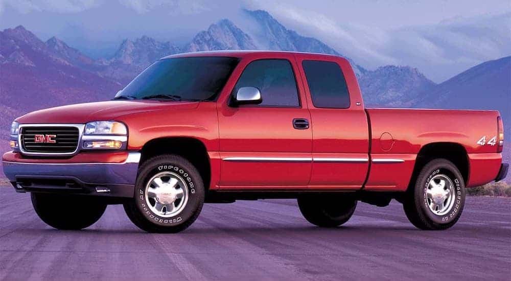 A red GMC 199 Sierra, the first used GMC Sierra, is parked in front of mountains.
