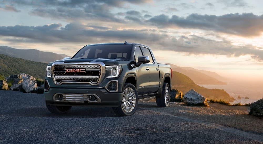 A gray 2019 GMC Sierra Denali is parked on a mountain at sunset.