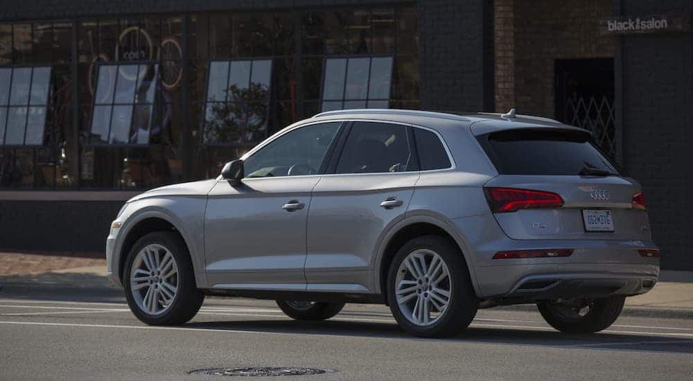 A silver 2020 Audi Q5 is parked in front of a bicycle shop.
