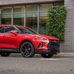 A man is walking towards a red 2020 Chevy Blazer RS that is parked on a street after winning the 2020 Chevy Blazer vs 2020 Nissan Murano comparison.
