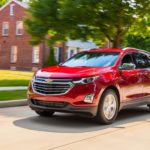 A red 2020 Chevy Equinox is driving in a suburban neighborhood.