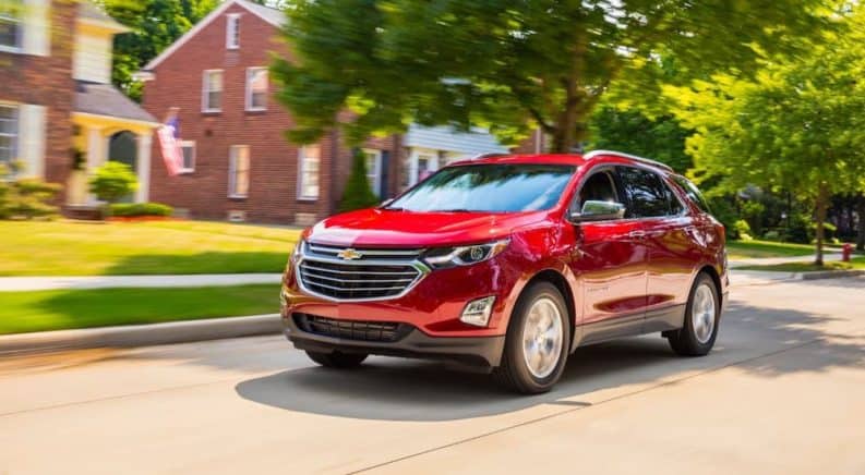 A red 2020 Chevy Equinox is driving in a suburban neighborhood.