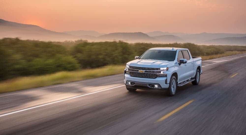 A white 2020 Chevy Silverado High Country is driving on a misty highway.