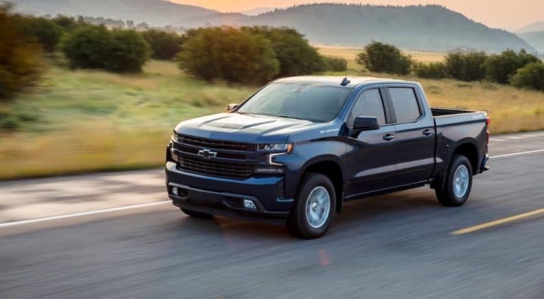 A blue 2020 Chevy Silverado RST is driving on highway with mountains in the distance.