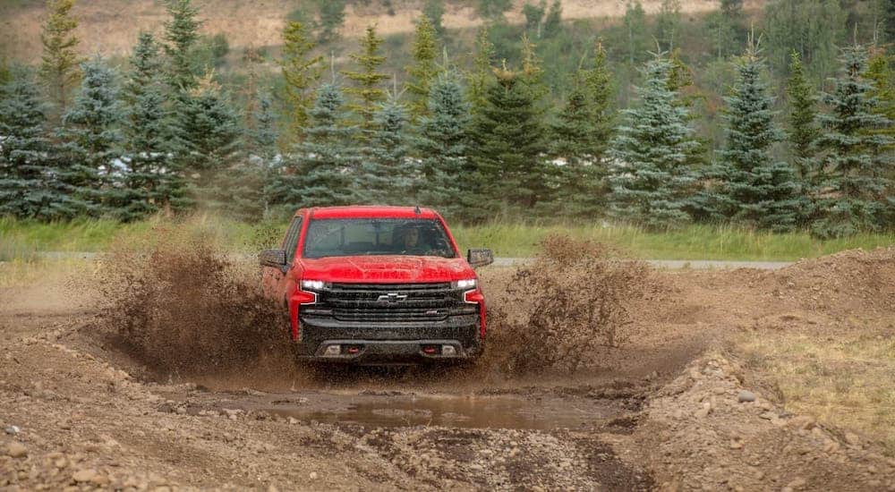 A red 2020 Chevy Silverado TrailBoss is driving though mud.