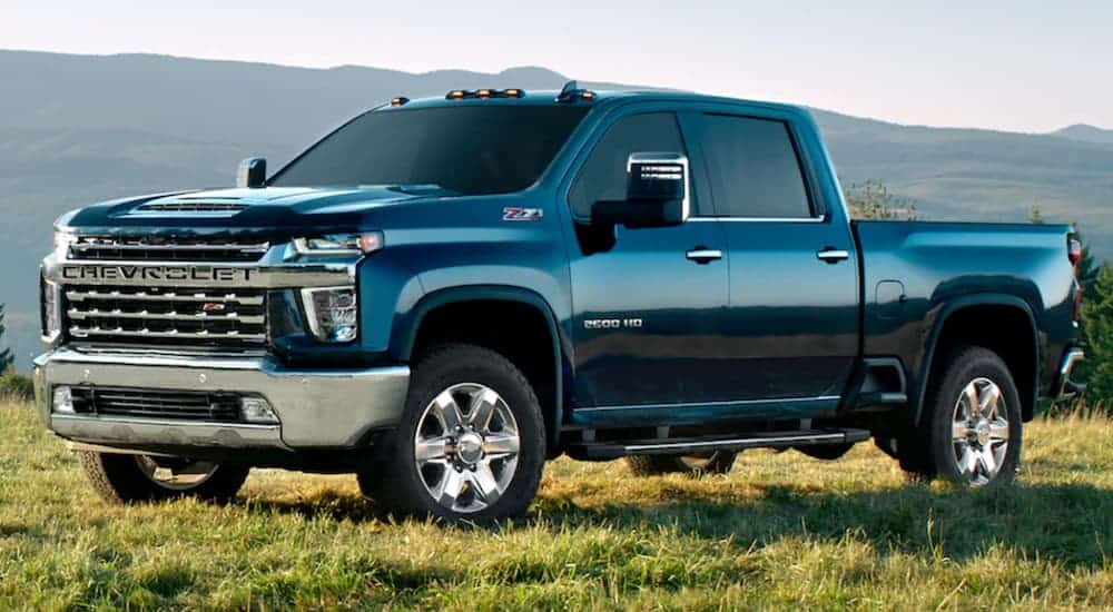 A black 2020 Chevy Silverado 2500HD is parked on grass in front of a hill.