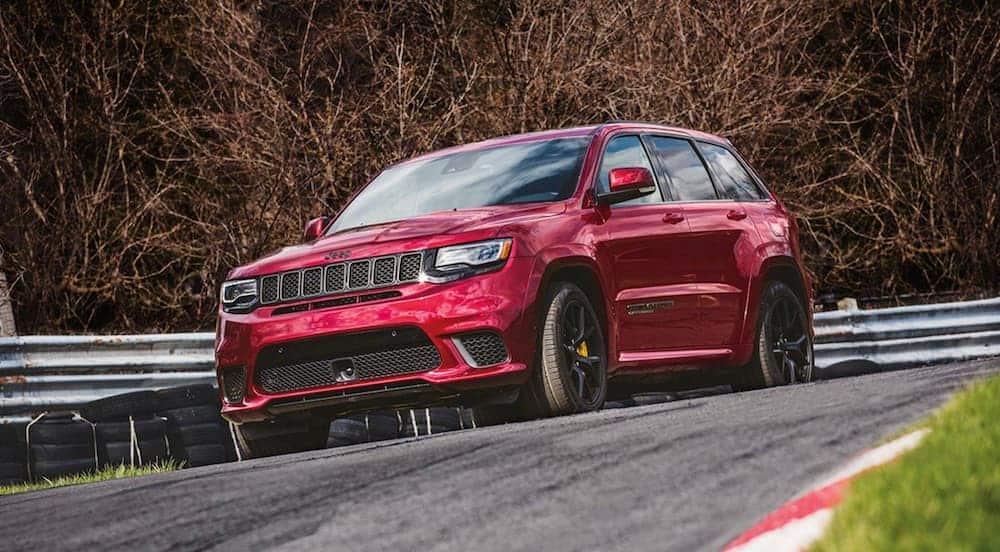 A red 2020 Jeep Grand Cherokee Trackhawk is driving around a corner on a racetrack.