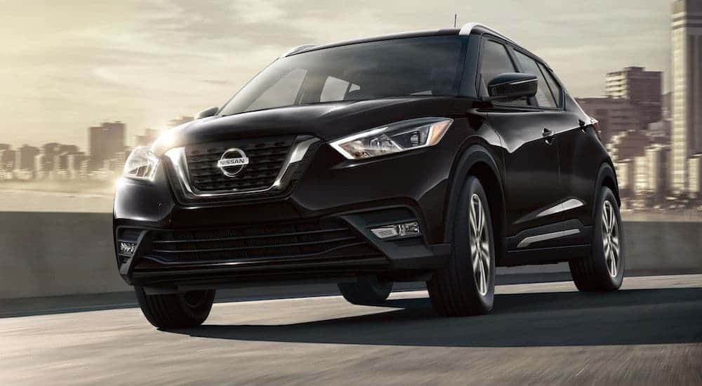 A black 2020 Nissan Kicks is driving through the city after leaving the Nissan dealer.