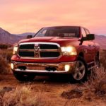 A red 2020 Ram 1500 Classic is parked in the desert at sunset.