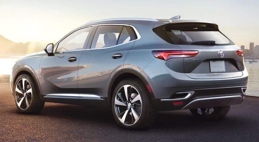 A silver 2021 Buick Envision is parked in front of a river and shown from the rear.