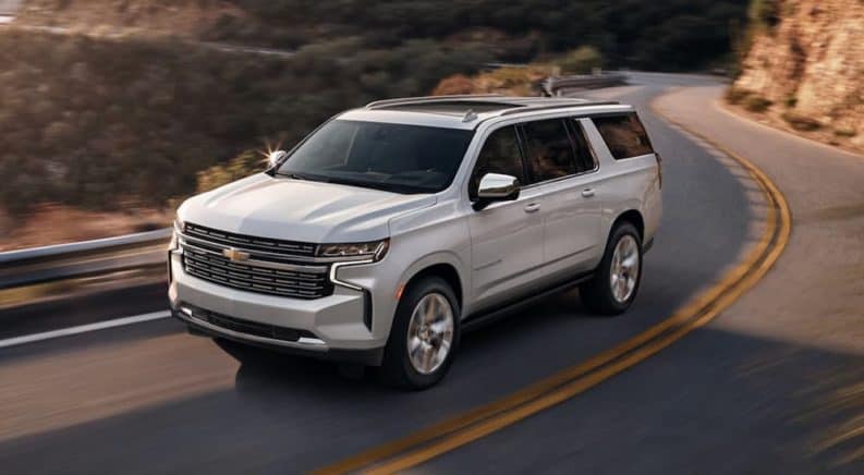 A white 2021 Chevy Suburban is driving on a winding mountain road.