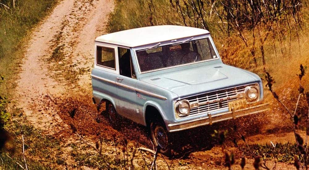 To compare the 2021 Ford Bronco vs 1966 Ford Bronco, here's a pale blue 1966 Ford Bronco driving on a dirt trail.
