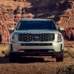 A silver 2021 Kia Telluride is facing forward in front of red rocks in the desert.