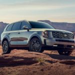 A silver 2021 Kia Telluride is parked in front of red rock formations.