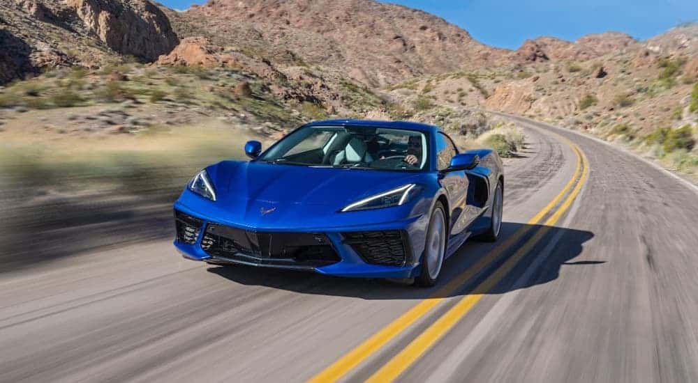 A blue 2021 Chevy Corvette is driving on a desert highway.