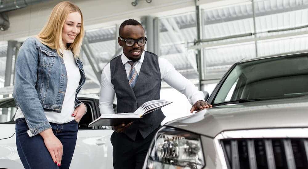A salesman is showing a woman a car inside a dealership.