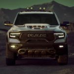 A silver 2021 Ram TRX, one of Ram's new vehicles for sale, is shown from the front in front of mountains at dusk.