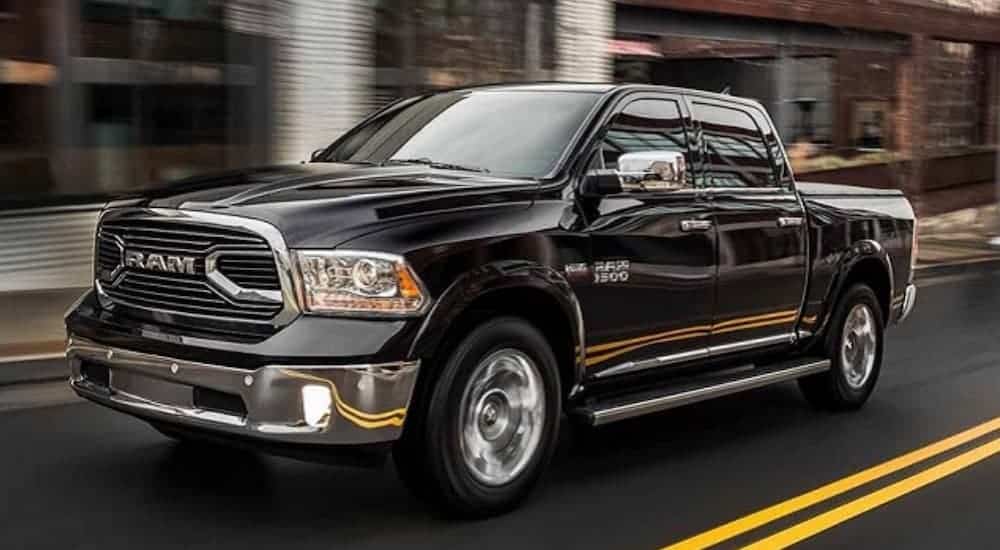 A popular used truck for sale, a black 2018 Ram 1500, is driving on a city street.