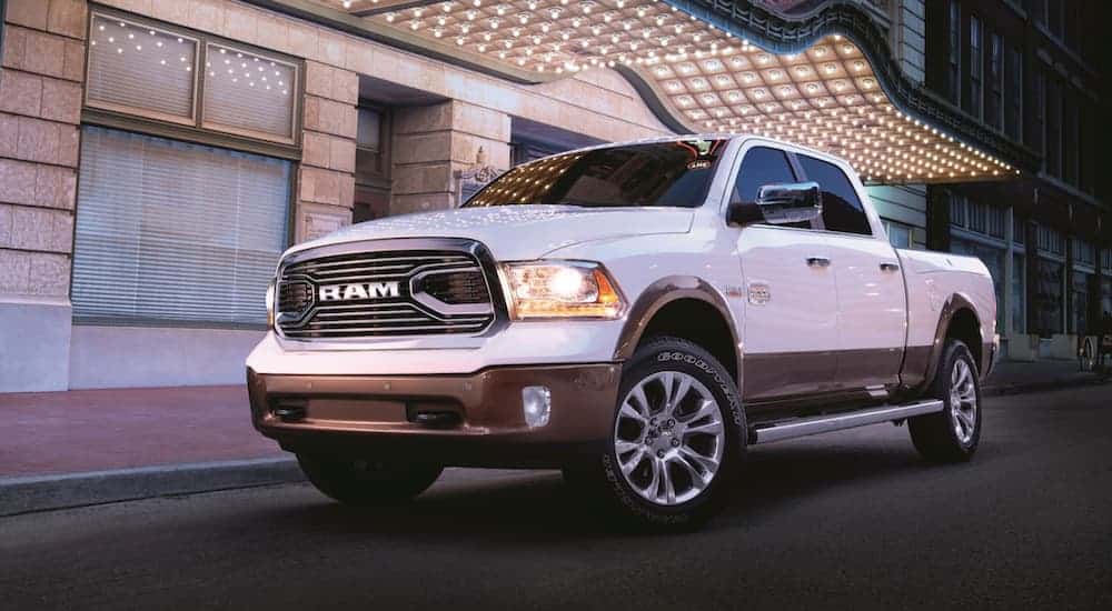 A white 2018 Ram 1500 is parked in front of a lit up building at night.