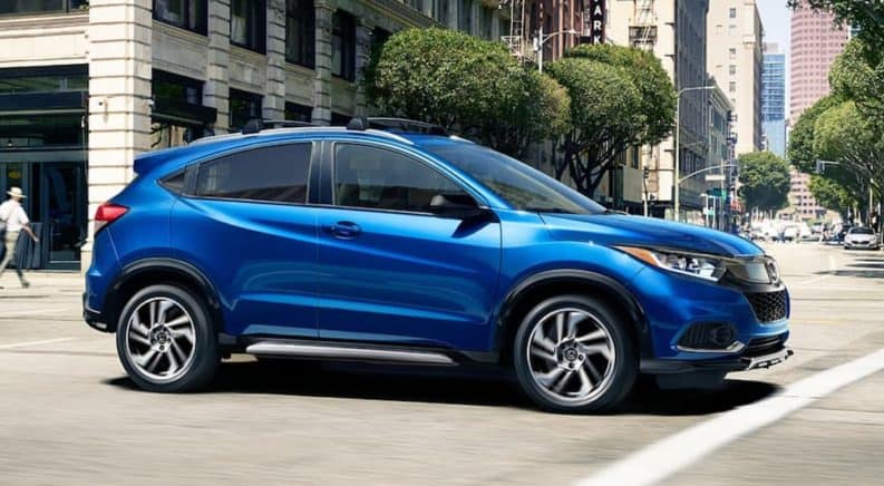 A blue 2020 Honda HR-V is driving through a city intersection in a comparison of the 2020 Honda HR-V vs 2020 Chevy Trax.