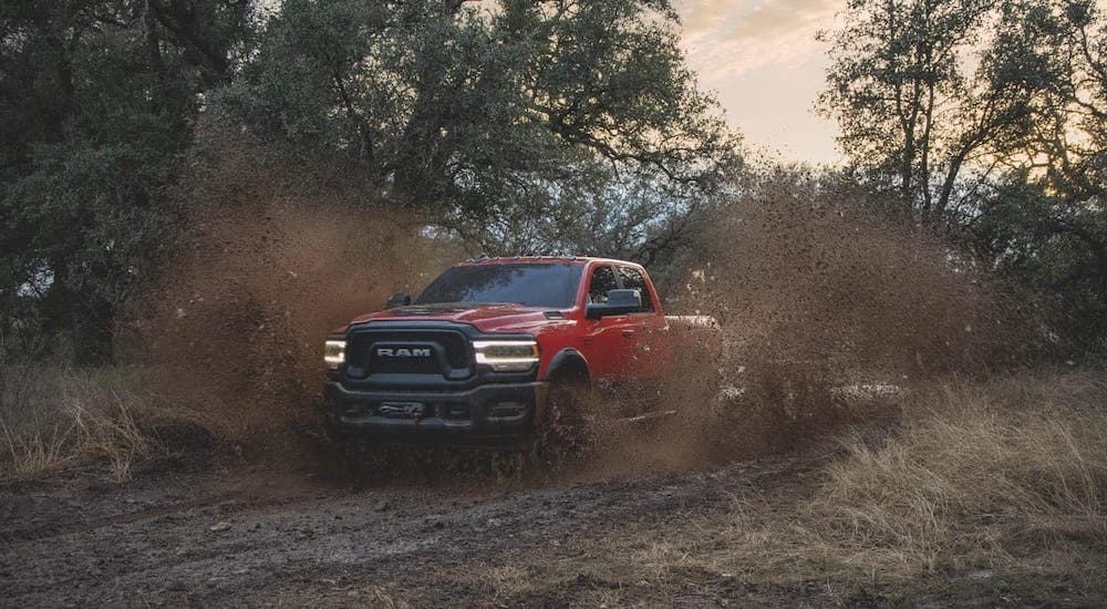 A red 2020 Ram 2500 Power Wagon is driving through mud after winning the 2020 Ram 2500 vs 2020 GMC Sierra 2500 comparison.