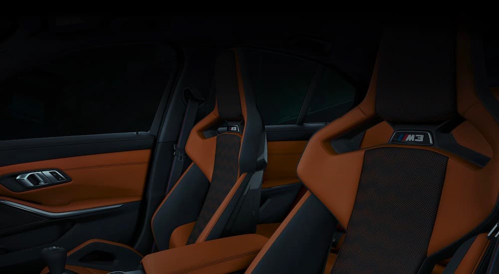 The front black and orange interior seats of the 2021 BMW M3 are shown.