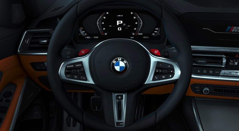 A close up of the black and silver steering wheel is shown in a 2021 BMW M3, a popular BMW sports car.