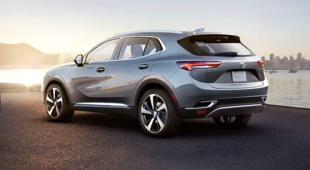 A grey 2021 Buick Envision is shown from the rear in front of a lake and sunset.