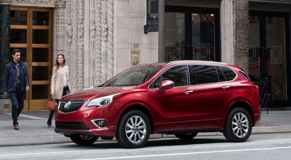 A red 2020 Buick Envision is parked in front of a city building.