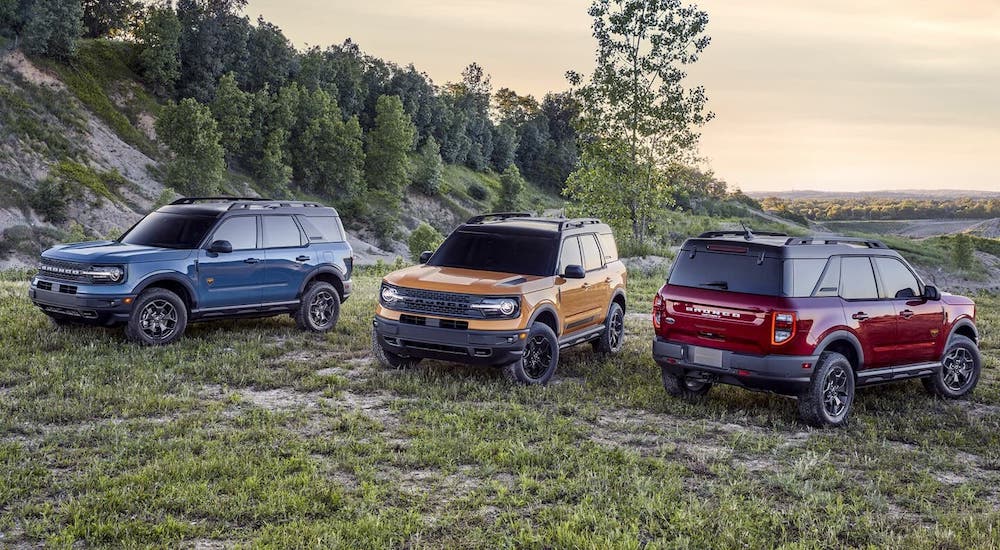 A blue, a yellow, and a red 2021 Ford Bronco Sport are parked on a mountain as part of the 2021 Ford Bronco vs 2021 Ford Bronco Sport comparison.