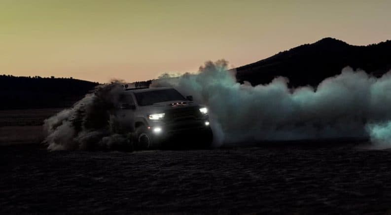 A silver 2021 Ram TRX is off-roading in the desert at dusk and kicking up a dust trail.
