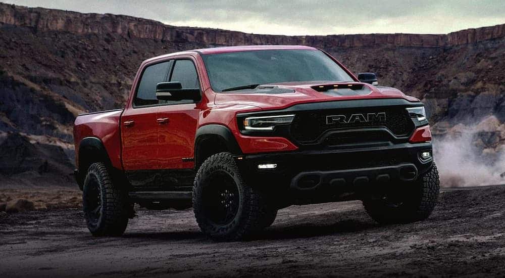 A red 2021 Ram TRX is parked in front of desert cliffs after winning the 2021 Ram TRX vs 2020 Ford Raptor comparison.