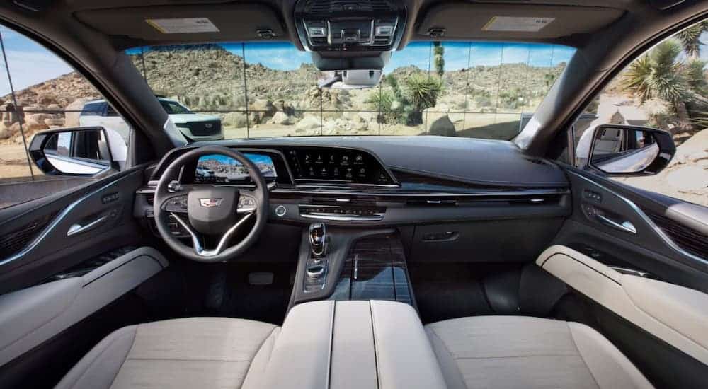 Coming to a Cadillac dealership, the dashboard and front seats of a 2021 Cadillac Escalade are shown.