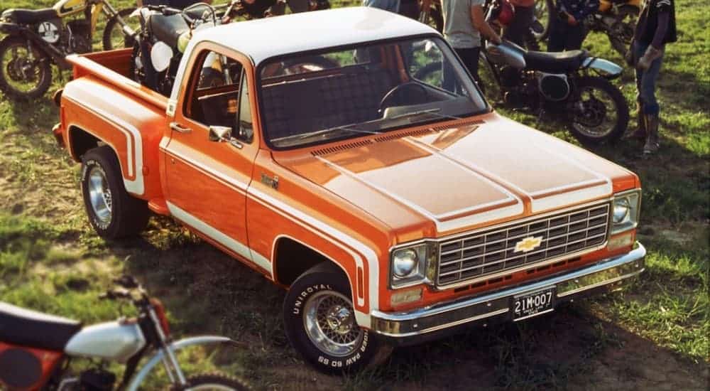 One of the most iconic Chevy trucks, a 1976 Chevy C10, is parked next to 1970s dirt bikes.
