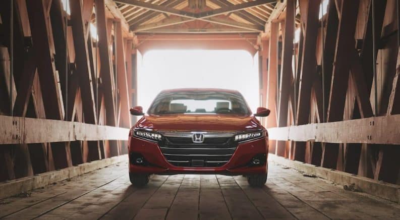 A red 2021 Honda Accord, a popular Honda car, is in a wooden, covered bridge.