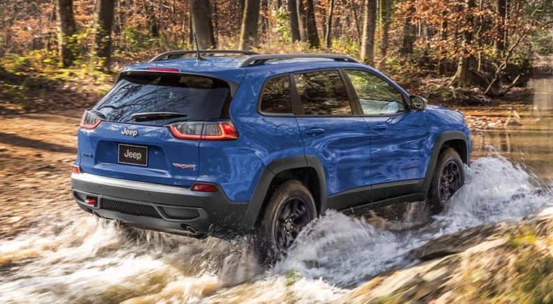 A blue 2021 Jeep Cheroke, a popular Jeep model, is off-roading through water.