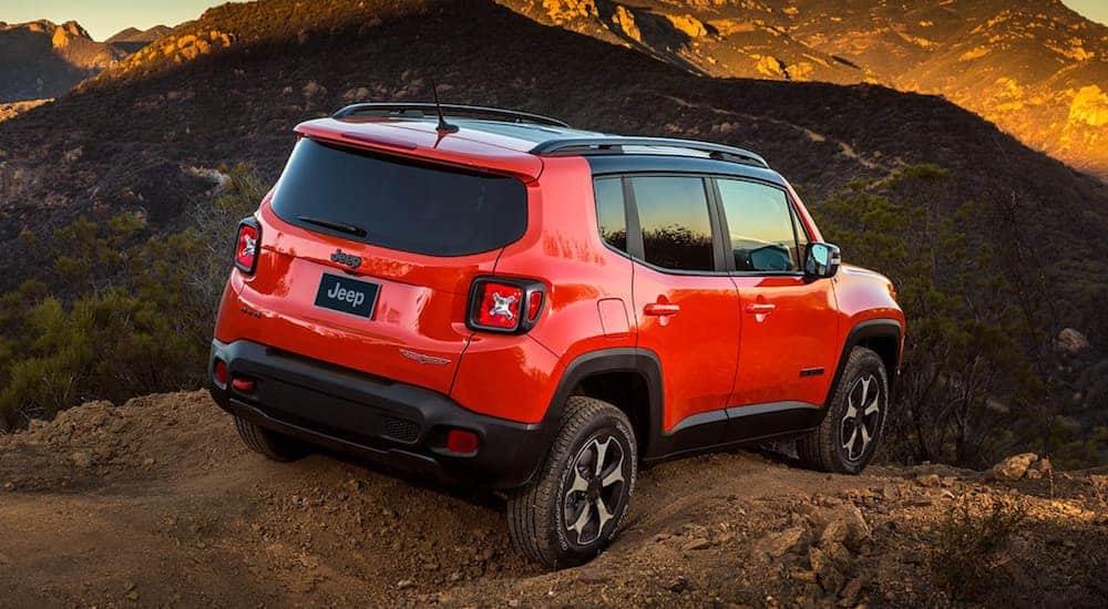 An orange 2021 Jeep Renegade is shown from the rear while off-roading on a desert mountain.